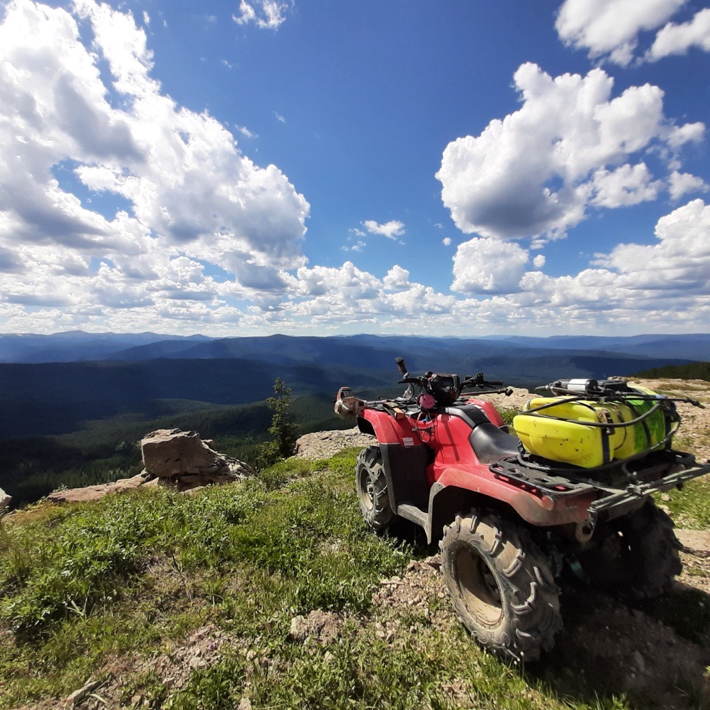 ATV with spray equipment overlooking mountain terrain